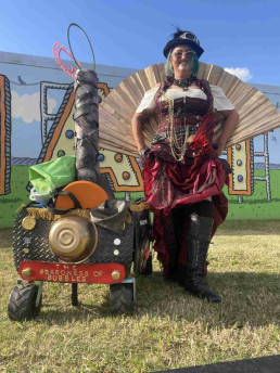 a woman with a big fan- she has a cart that looks like an old fasioned steam train and a corset very steampunk